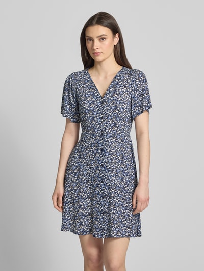 Frauenmodel trägt Minikleid aus reiner Viskose Modell 'EVIDA' von Only im Allover-Muster, tailliert, kurzarm, Ganzkörperansicht von vorne.
