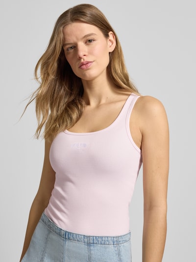 Frauenmodel trägt Tanktop in Ripp-Optik mit Label-Stitching von Guess Jeans aus Baumwoll-Elasthan-Mix, Slim-Fit, Pastellrosa, Nahaufnahme Oberkörper.