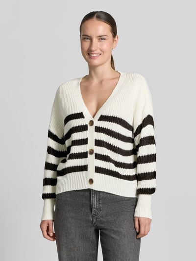 Frauenmodel trägt Oversized Strickjacke mit V-Ausschnitt Modell 'LEA' von VERO MODA in Creme mit schwarzen Streifen, grob gestrickt, Nahaufnahme Oberkörper.