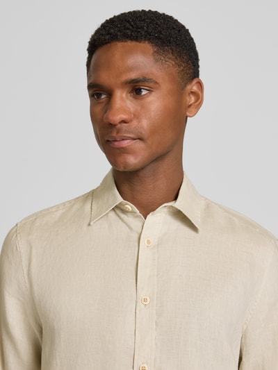 Męski model nosi Regular Fit Freizeithemd aus reinem Leinen od s.Oliver RED LABEL, efekt: jednolity kolor, kołnierzyk typu kent, listwa guzikowa jednorzędowa, naszywka z logo, długi rękaw, mankiet, materiał: len, jasnobeżowa faktura, zbliżenie na górną część ciała, przód.