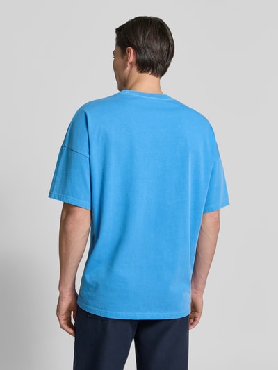 Männermodel trägt Herren T-Shirt mit geripptem Rundhalsausschnitt Modell 'FIZVALLEY' von American Vintage in Blau, Reine Baumwolle, Loose-Fit, Rückenlänge 72 cm, Ganzkörperansicht Rückansicht.