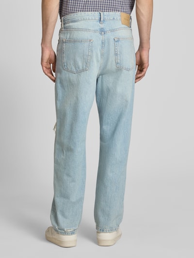 Männermodel trägt Loose-Fit Jeans aus reiner Baumwolle Modell 'FADE' von Only & Sons in heller Denim-Optik mit Destroyed-Details, Label-Patch, Nieten, 5-Pocket-Design, Ganzkörperansicht Rückansicht.