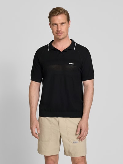 Männermodel trägt Regular Fit Poloshirt aus Strick von BOSS Green in Schwarz mit Strickoptik aus reiner Baumwolle, Ganzkörperansicht von vorne.