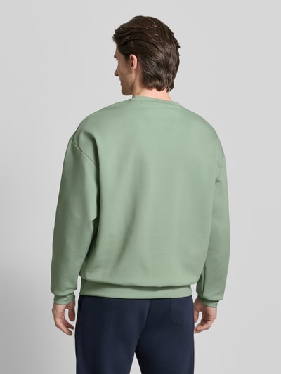Männermodel trägt Regular Fit Sweatshirt aus Baumwoll-Mix Modell 'STENSON' von BOSS Green in Hellgrün, Ganzkörperansicht Rückansicht.