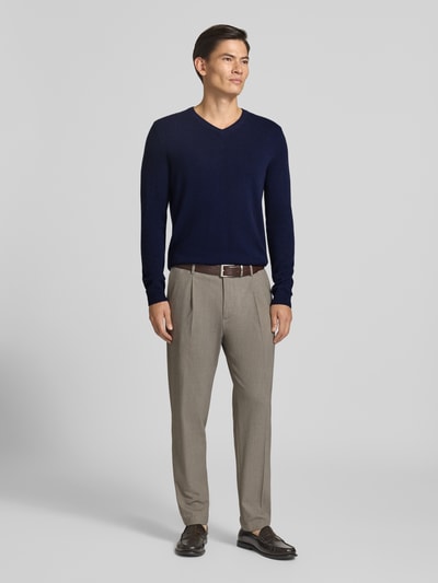 Männermodel trägt Strickpullover aus Kaschmir mit V-Ausschnitt von Christian Berg Men in Dunkelblau, kombiniert mit beigen Hosen, Ganzkörperansicht von vorne, Regular Fit, feine Textur, Rückenlänge und Ärmellänge bei Größe M je 71 cm.