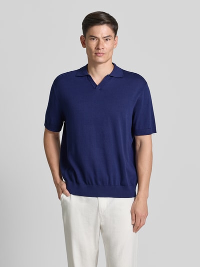 Männermodel trägt Relaxed Fit Poloshirt aus reiner Baumwolle Modell 'TORINO' von SELECTED HOMME in Dunkelblau, Ganzkörperansicht von vorne.
