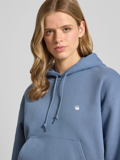 Kobiece model nosi Oversized Hoodie aus Baumwoll-Mix Modell 'CASEY' von Carhartt Work In Progress, mieszanka bawełny i elastanu, wyhaftowane logo, kangurka, kaptur z tunelem, krój oversized, gładki materiał, niebieski kolor, Nahaufnahme oberkörper.
