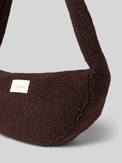 Produktfoto, Shoulder Bag aus Teddyfell von Studio Noos w kolorze ciemnobrązowym, futerko, naszywka z logo, główna przegroda z zamkiem błyskawicznym, szeroki pasek na ramię, przegródka wewnętrzna zapinana na zamek błyskawiczny, szerokość w rozmiarze 1: 48 cm, długość w rozmiarze 1: 24 cm, głębokość w rozmiarze 1: 10 cm, długość paska na ramię w rozmiarze 1: 90 cm.