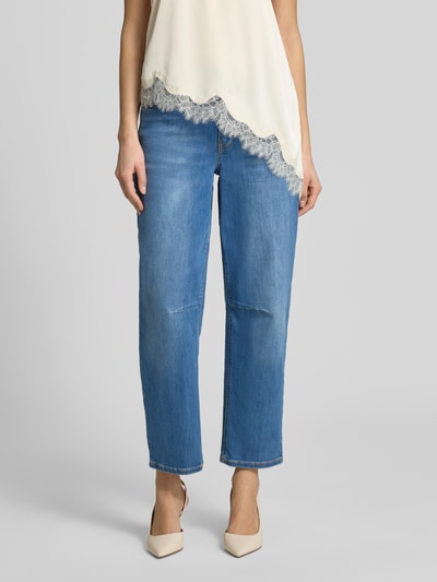 Modelka nosi Straight Fit Jeans im 5-Pocket-Design Modell 'Melly' von OPUS PANTS, mieszanka bawełny z dodatkiem streczu, krój relaxed fit, 5 kieszeni, zapięcie na guzik i zamek błyskawiczny, szerokość w rozmiarze 36/28: 39 cm, długość wewnętrzna nogawki w rozmiarze 36/28: 69 cm, niebieski denim, faktura gładka, widoczne szwy, widok z przodu na całe nogi.