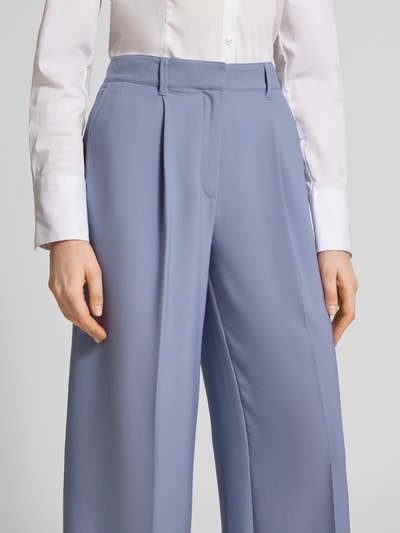 Frauenmodel trägt Wide Leg Bundfaltenhose mit Bügelfalten Modell 'C_TIWI2' von BOSS Orange in Hellblau mit seitlichen Taschen, Nahaufnahme Oberkörper.