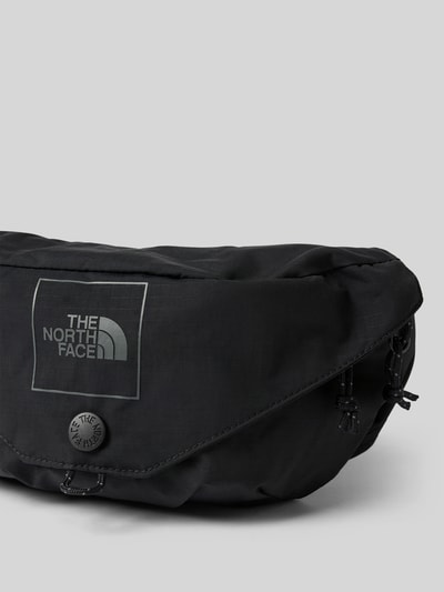 Produktfoto, schwarze Bauchtasche mit Logo-Print Modell 'Glen' von The North Face, Reißverschluss, glatte Textur, grauer Hintergrund