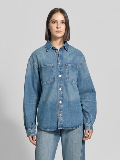 Frauenmodel trägt Oversized Hemdbluse aus reiner Baumwolle Modell 'Sahar' von Samsøe Samsøe in Denim-Optik mit Brusttaschen, Ganzkörperansicht von vorne.