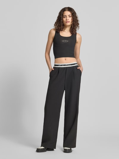 Frauenmodel trägt Slim Fit Top mit Logo-Print von ANOTHER COTTON LAB in Schwarz, elastischer Baumwoll-Mix, Rundhalsausschnitt, Ganzkörperansicht von vorne.