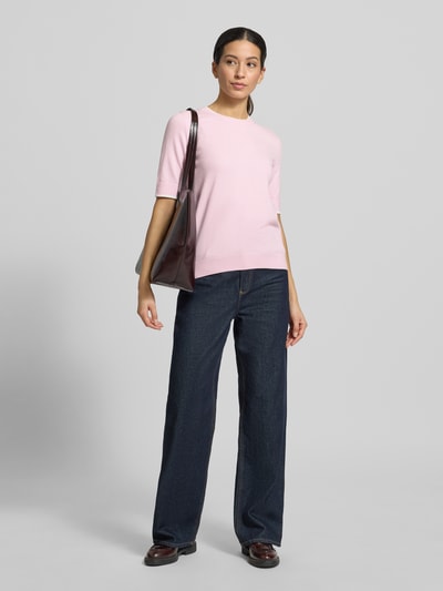 Kobiece model nosi Regular Fit Strickpullover mit Rundhalsausschnitt von More & More, mieszanka wiskozy, elastyczne wykończenia, półrękaw, krój regular fit, długość tyłu 54 cm, długość rękawa 27 cm, jasnoróżowy sweter z dzianiny, gładka tekstura, widok całej sylwetki z przodu.