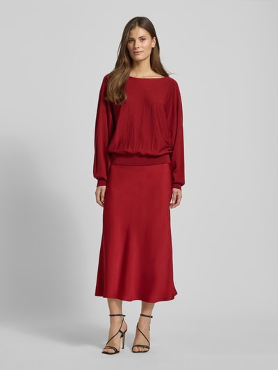 Vrouwenmodel draagt Midirock in A-lijn model 'URA' van Drykorn in rood, materiaal-mix met stretch, volledig lichaam van voren.