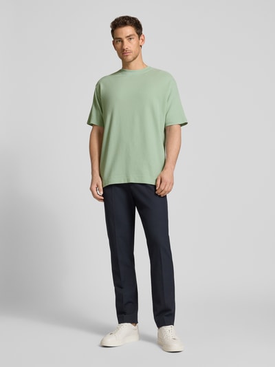 Männermodel trägt Relaxed Fit T-Shirt aus reiner Bio-Baumwolle Modell 'MAARKOS WAFFLE' von Armedangels in Optik: Unifarben mit Waffel-Struktur, Logo-Stitching, Rundhals, Kurzarm und Feinstrick, Ganzkörperansicht von vorne.
