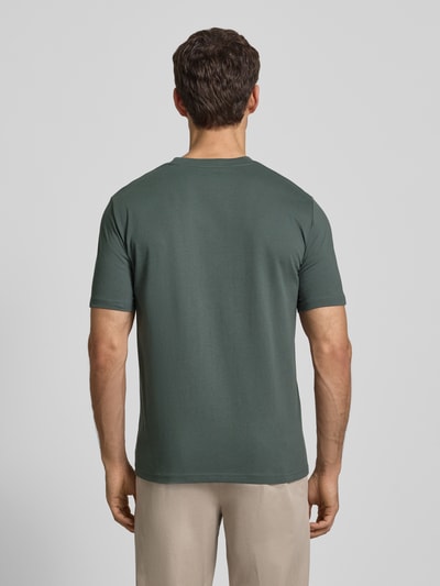 Męski model nosi T-shirt mit Label-Print von MARC O'POLO, bawełna, prosty krój, jednokolorowy, okrągły dekolt, detal z logo, długość tyłu 69 cm, rozmiar M, widok całej sylwetki od tyłu.
