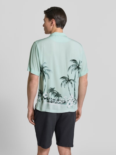 Męski model nosi Regular Fit Freizeithemd aus Viskose Modell 'RAYER_M' od BOSS Orange, jasnomiętowa koszula z nadrukiem palm i kwiatów, resortowy kołnierz, krótkie rękawy, czysta wiskoza, widok całej sylwetki od tyłu.