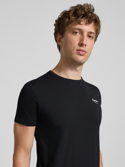 Männermodel trägt Slim Fit T-Shirt aus Baumwoll-Mix Modell 'ORIGINAL BASIC 3' von Pepe Jeans in Schwarz, Nahaufnahme Oberkörper, Melange Optik, unifarben, kurzarm, Rundhals, Label-Schriftzug, Jersey Material.