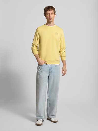 Männermodel trägt Regular Fit Pullover mit Logo-Stitching Modell 'Kane' von Blend in Gelb, Baumwoll-Mix, Ganzkörperansicht von vorne.