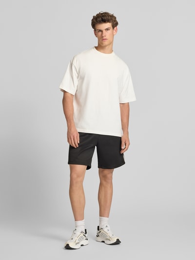 Männermodel trägt Regular Fit Sweatshorts mit elastischem Bund Modell 'RIBER' von Only & Sons, Optik: Unifarben, Regular-Fit, Applikation: Kontraststreifen, Bundabschluss: Elastisch mit Tunnelzug, Eingrifftaschen, Ganzkörperansicht von vorne.