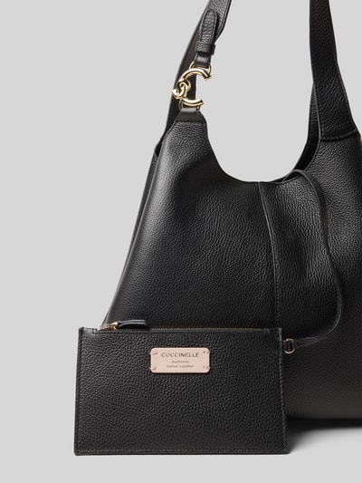 Produktfoto, czarna skórzana Handtasche mit Label-Detail od Coccinelle z magnetycznym zapięciem, rączką i złotym logo, faktura ziarnista, 26x16x14 cm, pasek 54 cm.
