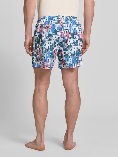 Männermodel trägt Badehose im Allover-Look Modell 'Vacay Villas' von BOARDIES mit elastischem Bund und Kordelzug, Ganzkörperansicht Rückansicht.