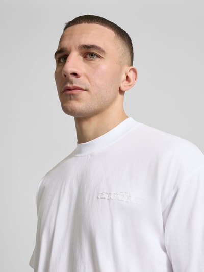 Männermodel trägt Regular Fit T-Shirt mit Logo-Detail von ANOTHER COTTON LAB in Weiß, reine Baumwolle, Nahaufnahme Oberkörper.