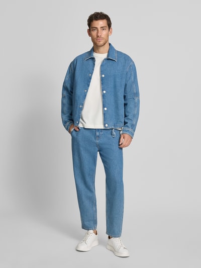 Männermodel trägt Wide Leg Tapered Fit Jeans aus Baumwoll-Ananas-Faser-Mix Modell 'ISAK' von Marc O'Polo Denim in blauer Denim-Optik, Ganzkörperansicht von vorne.