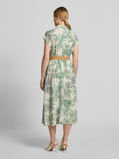 Frauenmodel trägt Tailliertes Freizeitkleid aus Lyocell-Viskose-Leinen-Mix von s.Oliver BLACK LABEL in Grün-Beige mit Palmenmuster, Ganzkörperansicht Rückansicht.