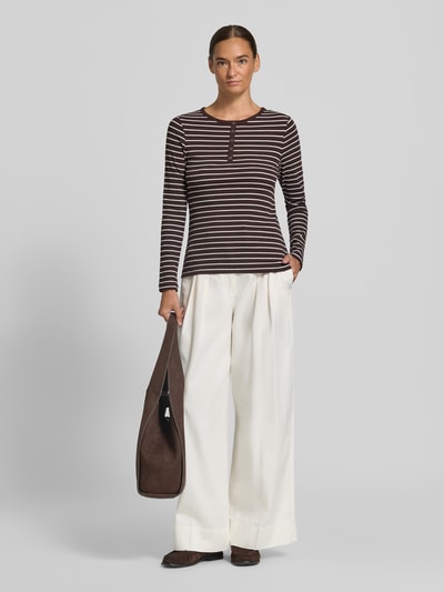 Modelka nosi Slim Fit Langarmshirt aus Baumwoll-Mix mit kurzer Knopfleiste od Christian Berg Woman, elastyczna bawełniana mieszanka, krój slim fit, okrągły dekolt, krótka listwa guzikowa, długi rękaw, długość pleców w rozmiarze S: 58 cm, przód całej sylwetki.