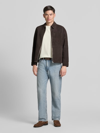 Männermodel trägt Regular Fit T-Shirt aus Baumwoll-Mix Modell 'TIBURT 240' von BOSS in Beige, kombiniert mit heller Jeans, Herren T-Shirt, Ganzkörperansicht von vorne.