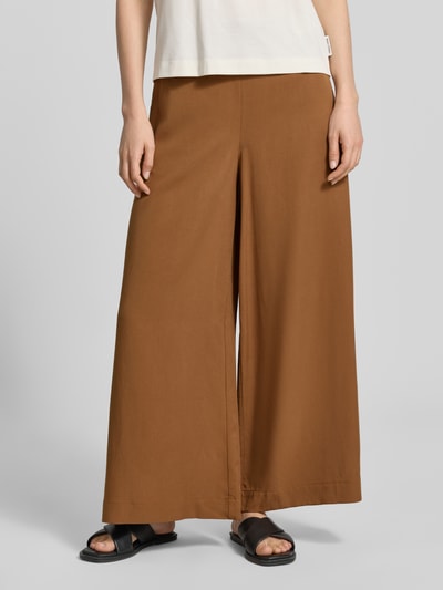 Frauenmodel trägt Cropped Wide Fit Culotte aus Lyocell-Leinen-Mix von Marc O'Polo, Optik: Unifarben, Passform: Wide-Fit, Bundhöhe: Mid, Länge: Cropped, Details: Bügelfalte, Bundabschluss: Elastisch, Material: Lyocell-Leinen-Mix, warme braune Farbe, glatte Textur, Nahaufnahme Unterkörper