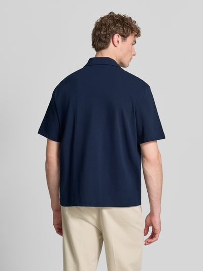 Männermodel trägt Relaxed Fit Freizeithemd aus reiner Baumwolle von Lacoste in Dunkelblau, kurzarm, unifarben, Ganzkörperansicht Rückansicht.