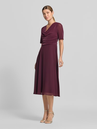 Kobiece modelka nosi Fit and Flare Cocktailkleid mit Wasserfallausschnitt od Vera Mont w kolorze bordowym, połyskliwy materiał góry, gładka spódnica, całkowity widok z przodu.