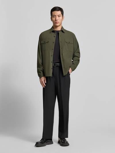Männermodel trägt Hemdjacke mit Knopfleiste von CRUNA in Olivgrün, Material-Mix mit Stretch, Regular Fit, Kentkragen, Brusttaschen, Ganzkörperansicht von vorne.