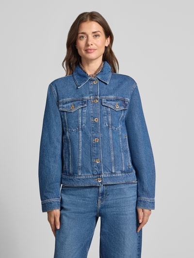 Kobiece model prezentuje kurtkę jeansową Jeansjacke mit Brusttaschen Modell 'Saima' od MOS MOSH z czystej bawełny, krój regular fit, wykładany kołnierz, kieszenie na piersi, listwa guzikowa, niebieski denim, gładka tekstura, przód, ujęcie całej sylwetki.