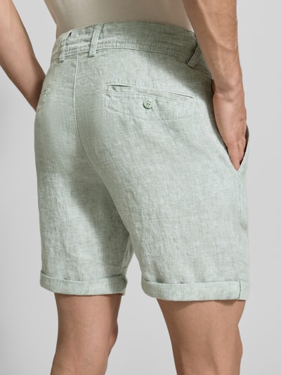 Männermodel trägt Leinenshorts mit Bindegürtel und Gesäßtaschen von MCNEAL, len, krój straight fit, zakładka, wyhaftowane logo, długość wewnętrzna nogawki 16 cm, szerokość w rozmiarze M 45 cm, wpuszczane kieszenie, wpuszczana kieszeń z tyłu z guzikem, zakładka na dole, zapięcie na guzik i zamek błyskawiczny, widok z tyłu, całe nogi.