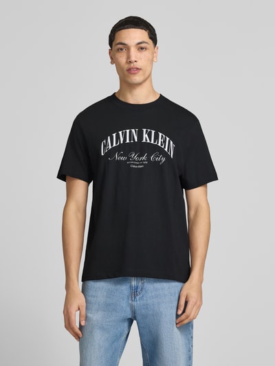 Männermodel trägt T-Shirt mit Label-Stitching von Calvin Klein Jeans in Schwarz aus Reine Baumwolle, Slim-Fit, Rundhalsausschnitt, Ganzkörperansicht von vorne. Rückenlänge bei Größe M: 70 cm.