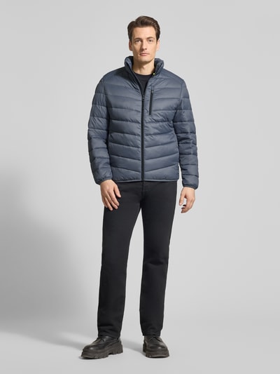 Männermodel trägt Regular Fit Steppjacke mit vertikaler Reißverschlussbrusttasche von Tom Tailor Denim in Optik: Unifarben, Ganzkörperansicht von vorne.