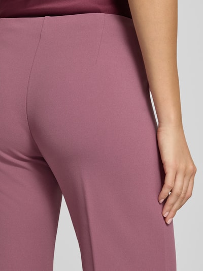 Frauenmodel trägt Flared Fit Stoffhose mit Bügelfalten von Rinascimento in Altrosa, glatte Struktur, elastischer Bund, Detailaufnahme, Damen Stoffhose von Rinascimento, Material-Mic mit Stretch-Anteil, Bundweite S 38 cm, Innenbeinlänge S 85 cm.