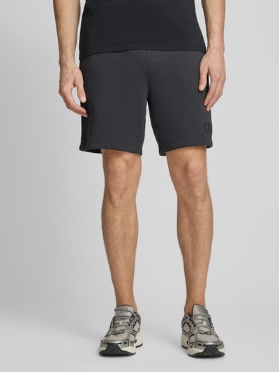 Männermodel trägt Sweatshorts mit elastischem Bund von GAP aus Baumwoll-Mix mit Logo, Relaxed-Fit, Ganzkörperansicht von vorne.