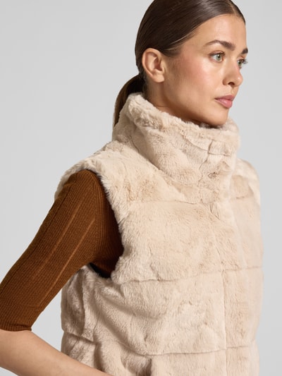 Vrouwenmodel draagt Weste aus Kunstfell mit Steppnähten van monari in beige, regular fit met staande kraag, detailopname bovenlichaam.