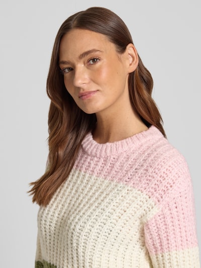 Frauenmodel trägt Strickpullover mit Rundhalsausschnitt von More & More im Grobstrick, Material-Mix mit Baumwoll-Anteil, Nahaufnahme Oberkörper.