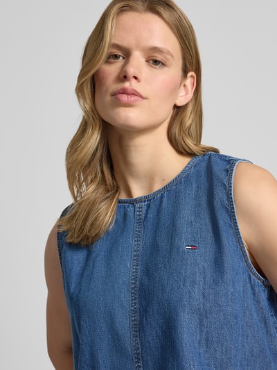 Frauenmodel trägt Relaxed Fit Denim Blusentop aus reiner Baumwolle von Tommy Jeans in klassischer Denim-Optik mit Rundhals und Tunnelzug, Nahaufnahme Oberkörper.