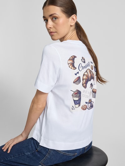 Kobiece modelka ma na sobie T-shirt mit Rundhalsausschnitt od Rich & Royal z nadrukiem, wykonany z bawełny, krój regular fit, długość tyłu w rozmiarze S: 58 cm, ujęcie całej sylwetki z tyłu.