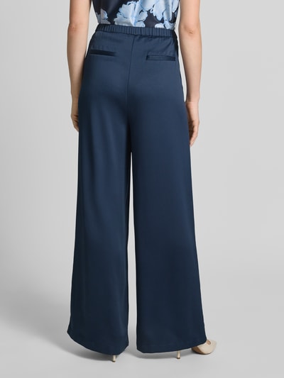 Vrouwenmodel draagt Loose Fit Pants met elastische tailleband en steekzakken van Christian Berg Cocktail in donkerblauw, gladde stof, losse snit, detailopname van achteraan.