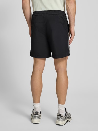 Männermodel trägt Regular Fit Shorts mit Label-Applikation Modell 'COLAS262S' von HUGO, Optik: Unifarben, Ganzkörperansicht Rückansicht.