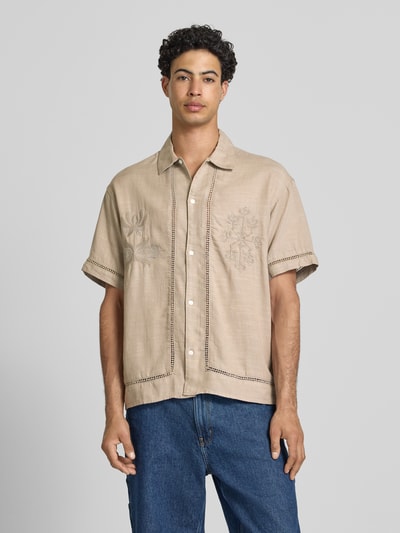 Männermodel trägt Relaxed Fit Freizeithemd aus Lyocell-Mix Modell 'Menton' von Jack & Jones in Beige mit floralen Stitchings, Kurzärmelig, Kentkragen, durchgehende Knopfleiste, Loch-Stickereien, Baumwoll-Lyocell-Mix, Ganzkörperansicht von vorne. Rückenlänge 72 cm, Schulterbreite 52 cm, Ärmellänge 25 cm bei Größe M.