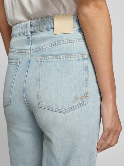 Frauenmodel trägt Wide & Loose Fit Jeans von BOSS Orange in hellblauer Jeans-Optik, Detailaufnahme Rückansicht.